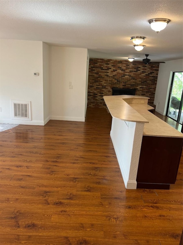 kitchen with brick wall, a textured ceiling, a center island, and dark hardwood / wood-style floors