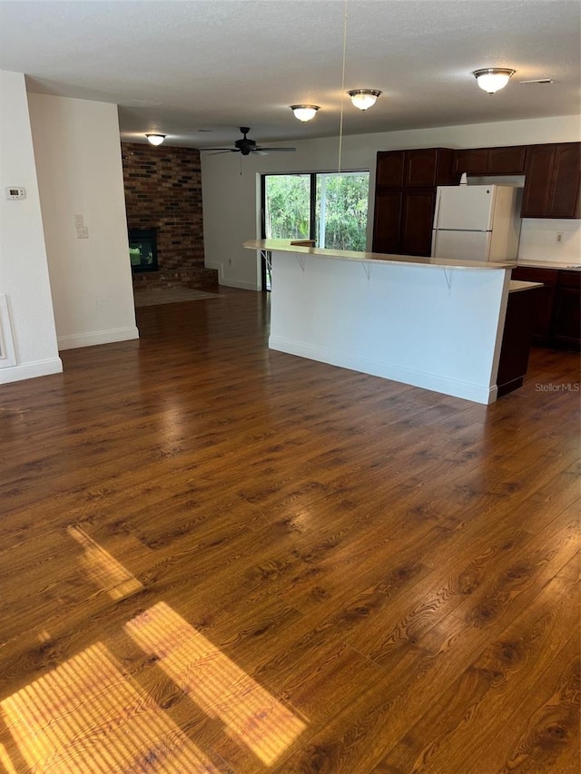 unfurnished living room featuring dark wood-type flooring, a fireplace, and ceiling fan