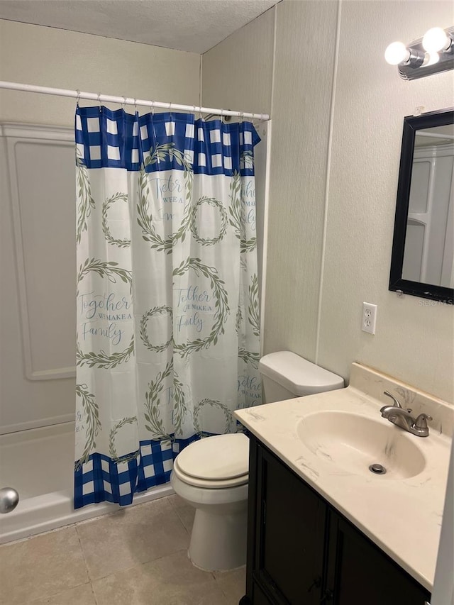 bathroom featuring a textured ceiling, walk in shower, toilet, vanity, and tile patterned flooring