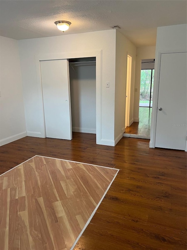 unfurnished bedroom featuring a closet, a textured ceiling, and dark hardwood / wood-style floors