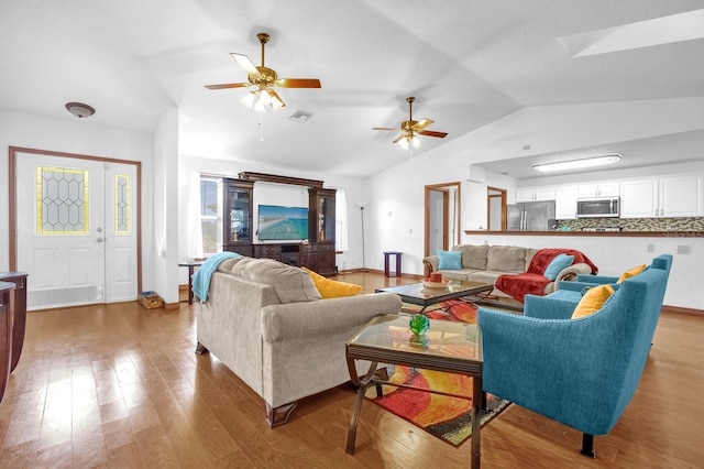 living room with vaulted ceiling, light wood-type flooring, and ceiling fan