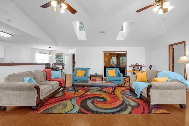 living room featuring vaulted ceiling with skylight, light hardwood / wood-style flooring, and ceiling fan