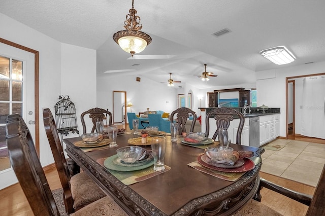 dining area with light hardwood / wood-style floors, a textured ceiling, and vaulted ceiling