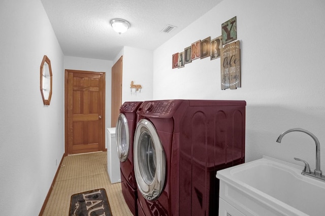 laundry area with sink, a textured ceiling, and washer and clothes dryer