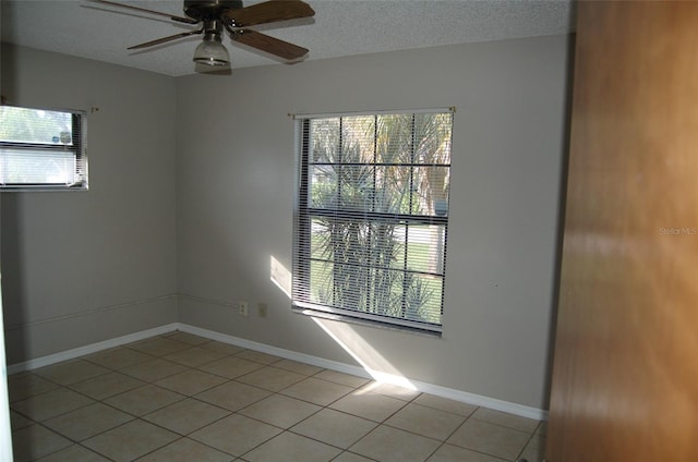 spare room with ceiling fan, a textured ceiling, and light tile patterned floors