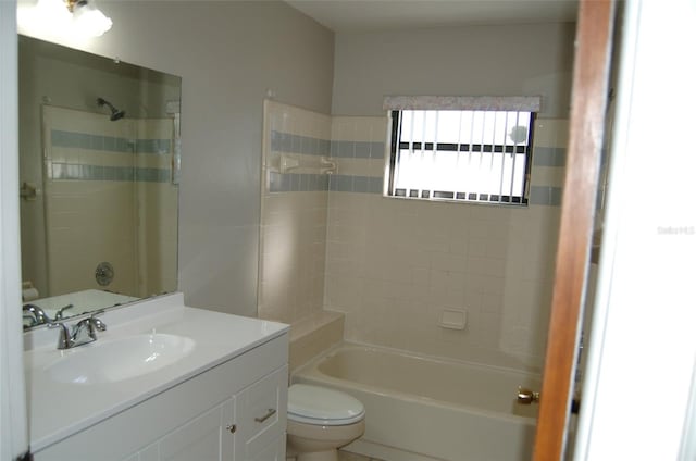 full bathroom featuring tiled shower / bath, vanity, and toilet