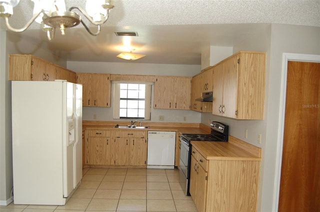 kitchen with white appliances, light brown cabinetry, light tile patterned flooring, sink, and a textured ceiling