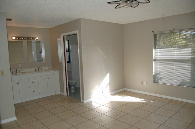 bathroom with ceiling fan, a textured ceiling, toilet, vanity, and tile patterned floors