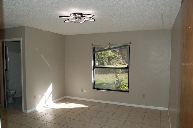 empty room with a textured ceiling, light tile patterned flooring, and ceiling fan