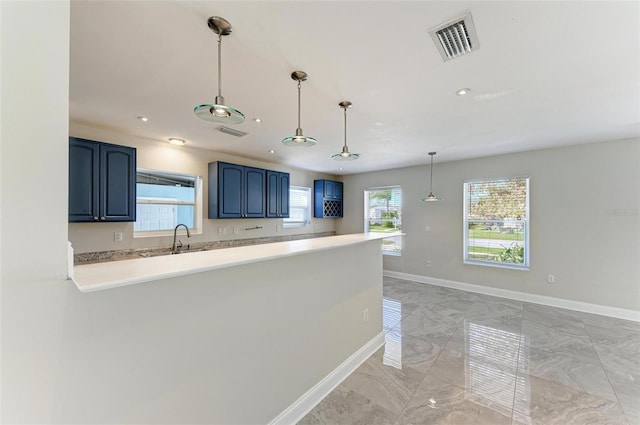 kitchen with kitchen peninsula, sink, pendant lighting, and blue cabinets