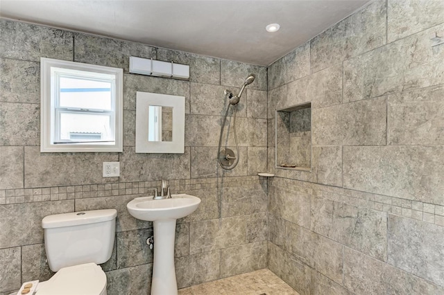 bathroom featuring tile walls, tiled shower, and toilet