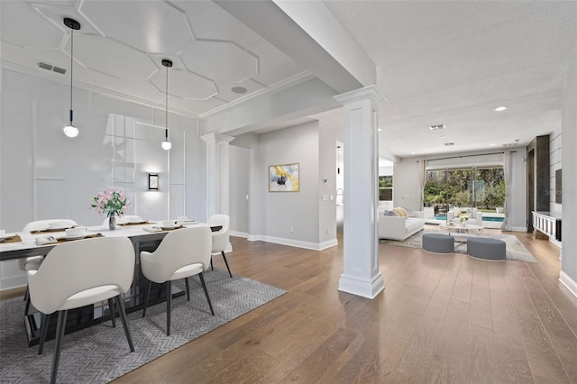 dining area with ornamental molding, dark hardwood / wood-style flooring, decorative columns, and a textured ceiling