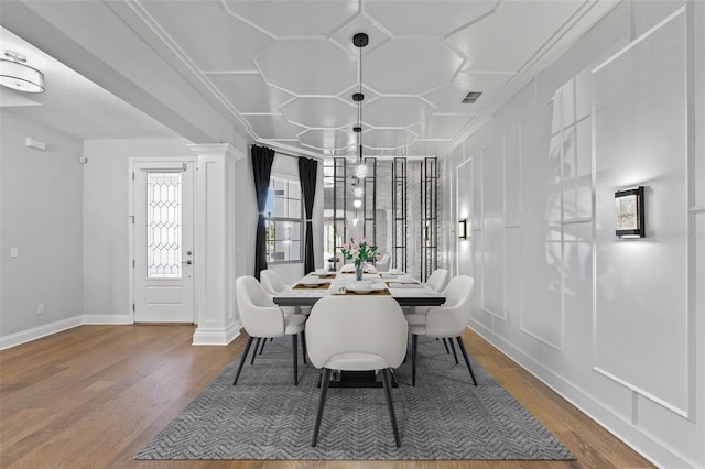 dining room featuring crown molding, wood-type flooring, and decorative columns