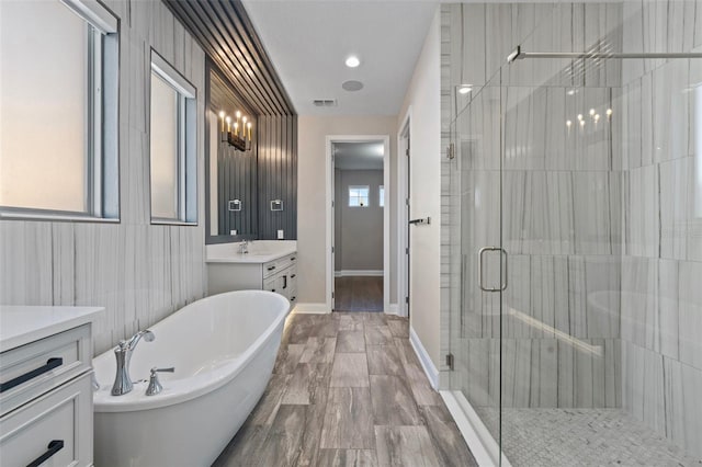 bathroom with vanity, hardwood / wood-style floors, plenty of natural light, and plus walk in shower