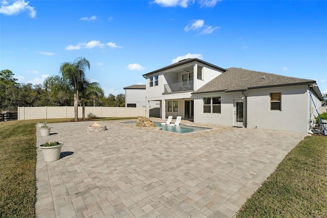 back of property featuring a patio, a balcony, pool water feature, a yard, and a fenced in pool