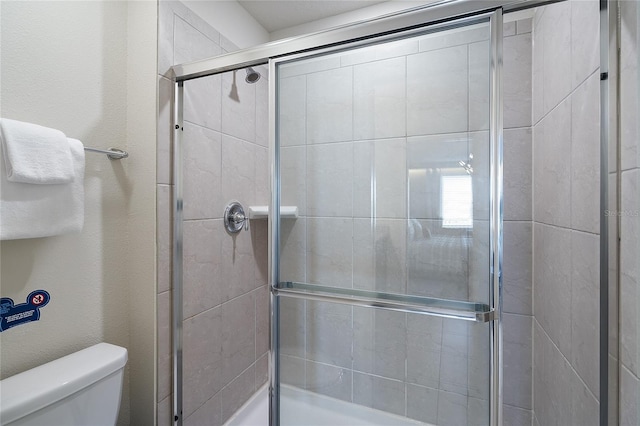 bathroom with toilet and a shower with shower door