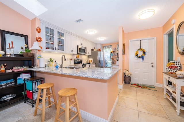 kitchen with a breakfast bar area, white cabinetry, kitchen peninsula, and stainless steel appliances