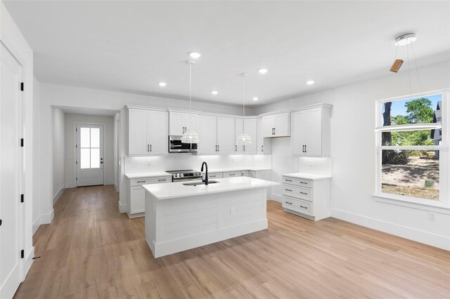 4190 Rossmore Dr, Orlando, FL 32810 - kitchen with appliances with stainless steel finishes, an island with sink, baseboards, light wood-type flooring, and a sink