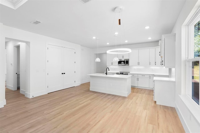 kitchen with sink, hanging light fixtures, white cabinetry, light hardwood / wood-style floors, and stainless steel appliances