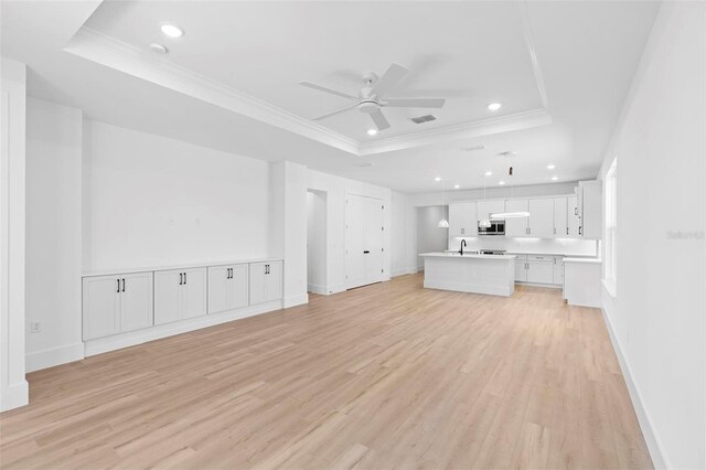 4190 Rossmore Dr, Orlando, FL 32810 - unfurnished living room featuring a raised ceiling, crown molding, ceiling fan, light wood finished floors, and recessed lighting
