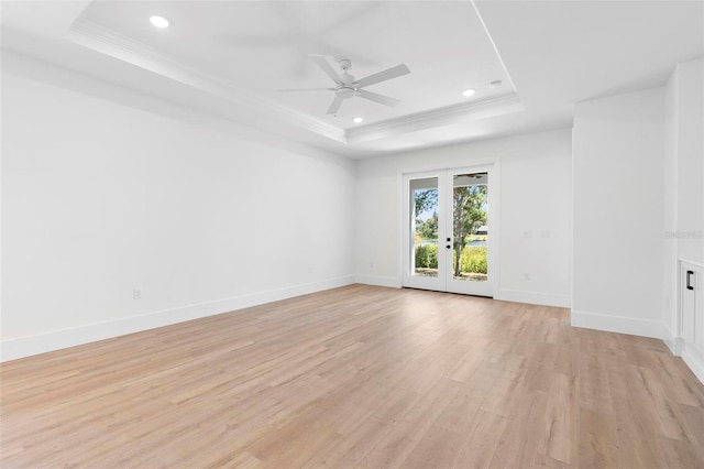 unfurnished room featuring french doors, light hardwood / wood-style floors, a tray ceiling, and ceiling fan