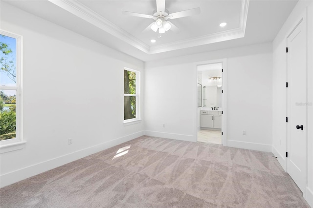 unfurnished bedroom with ensuite bath, a raised ceiling, multiple windows, and ceiling fan