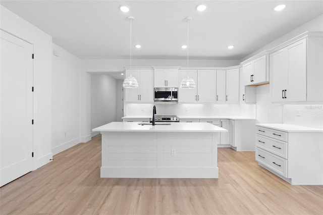 kitchen featuring light wood-type flooring, an island with sink, and hanging light fixtures