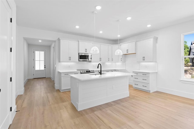 kitchen featuring a healthy amount of sunlight, appliances with stainless steel finishes, sink, and a kitchen island with sink