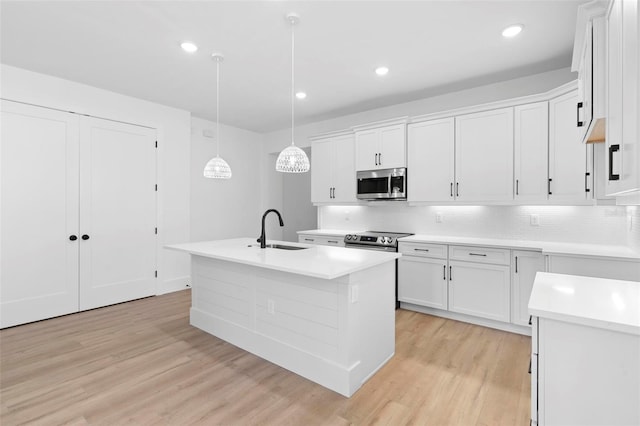 kitchen featuring a center island with sink, sink, white cabinetry, and stainless steel appliances