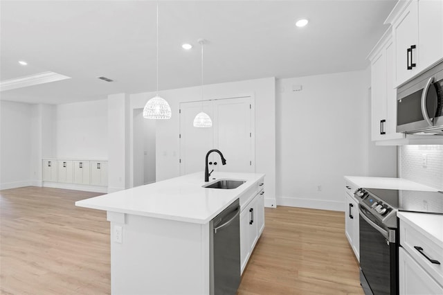 kitchen with sink, hanging light fixtures, stainless steel appliances, light hardwood / wood-style flooring, and a center island with sink