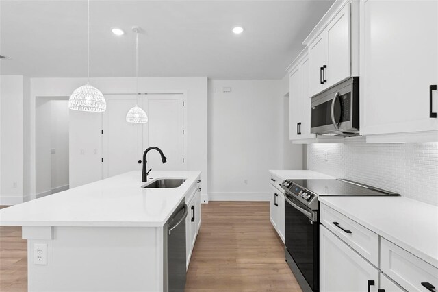 4190 Rossmore Dr, Orlando, FL 32810 - kitchen featuring appliances with stainless steel finishes, a sink, baseboards, light wood-style floors, and light countertops