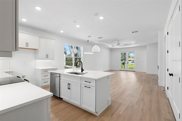 4190 Rossmore Dr, Orlando, FL 32810 - kitchen featuring dishwasher, a sink, light wood finished floors, a kitchen island with sink, and white cabinets