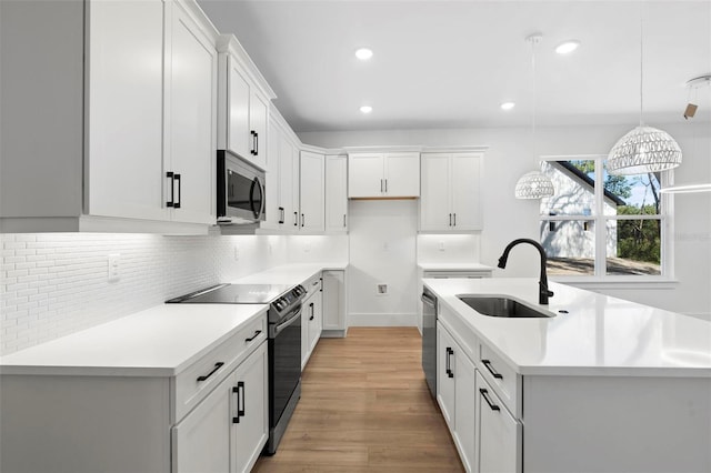 kitchen featuring white cabinetry, stainless steel appliances, sink, and decorative light fixtures