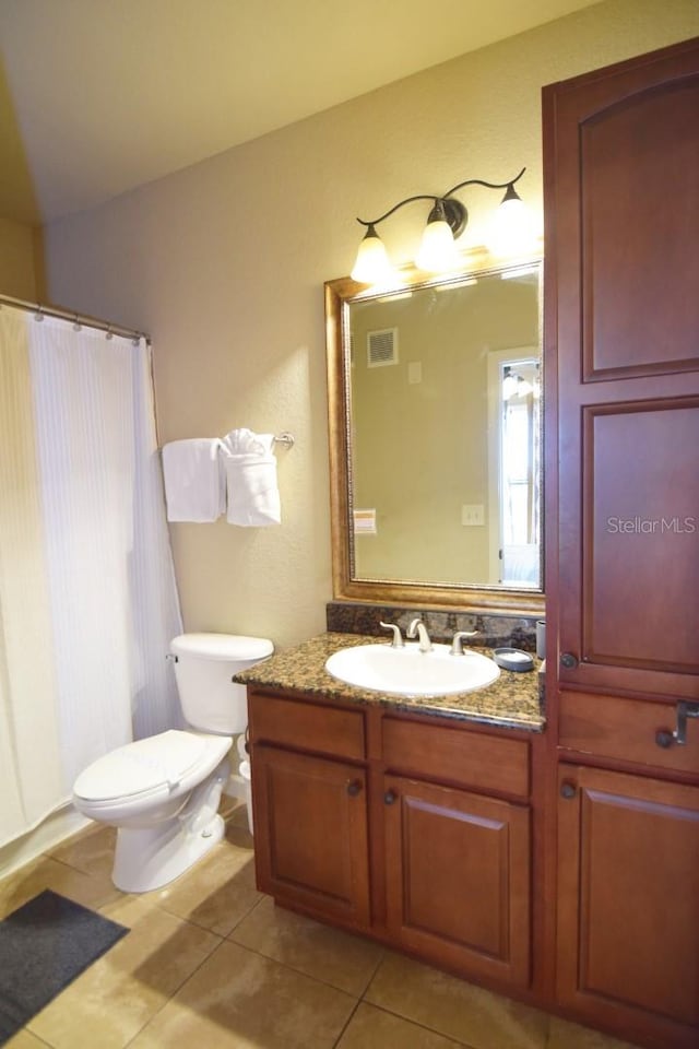 bathroom with toilet, curtained shower, vanity, and tile patterned flooring