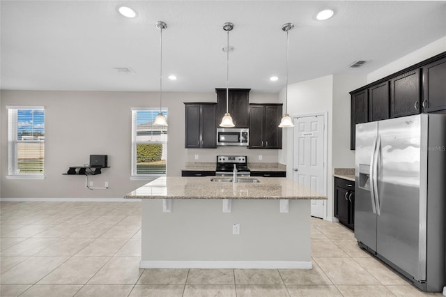 kitchen with decorative light fixtures, stainless steel appliances, and an island with sink