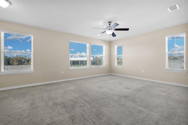 carpeted spare room featuring ceiling fan and plenty of natural light