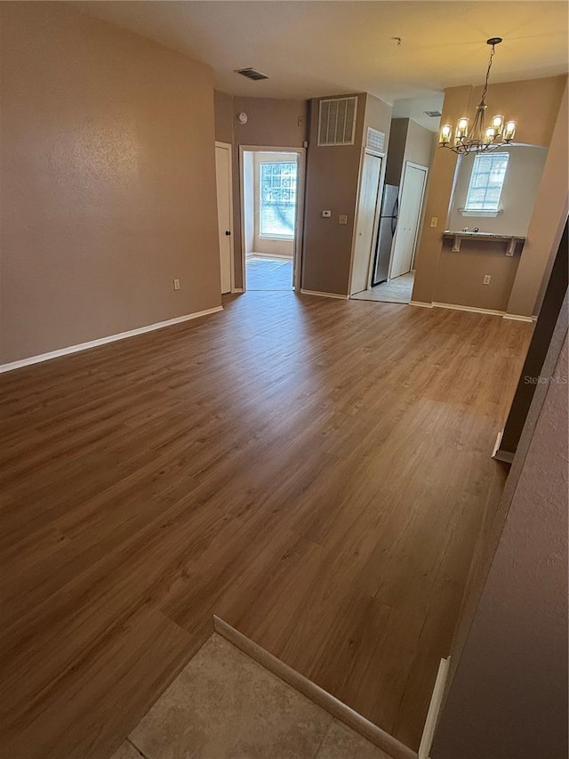 unfurnished room with hardwood / wood-style floors and an inviting chandelier