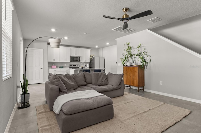 living room with a textured ceiling, sink, and ceiling fan