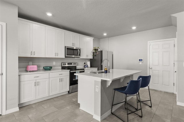 kitchen with white cabinetry, appliances with stainless steel finishes, sink, and a kitchen island with sink