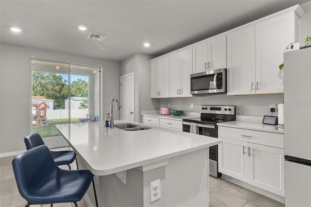 kitchen featuring appliances with stainless steel finishes, sink, a kitchen breakfast bar, white cabinets, and a kitchen island with sink