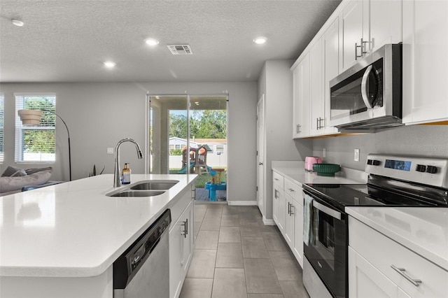 kitchen featuring sink, an island with sink, stainless steel appliances, and a healthy amount of sunlight