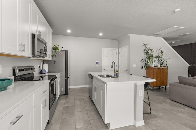 kitchen with appliances with stainless steel finishes, sink, a kitchen breakfast bar, white cabinets, and a center island with sink