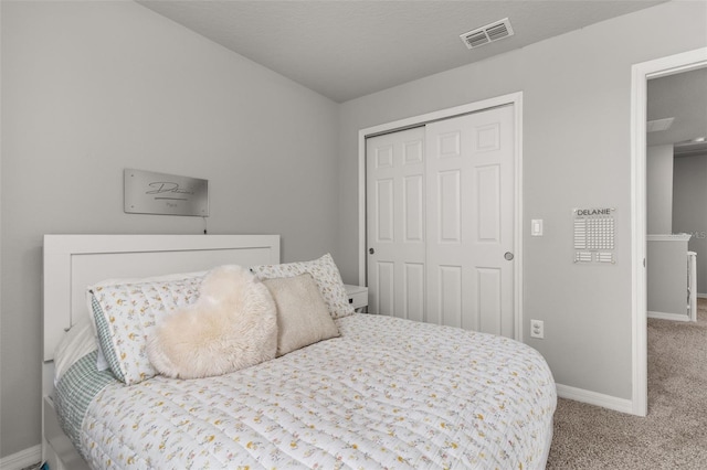 bedroom with a textured ceiling, light colored carpet, and a closet