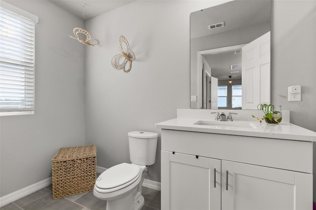 bathroom with toilet, vanity, plenty of natural light, and tile patterned flooring