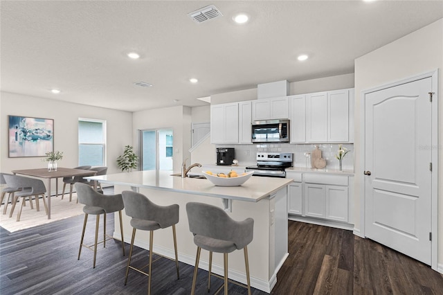 kitchen featuring appliances with stainless steel finishes, an island with sink, decorative backsplash, sink, and white cabinetry