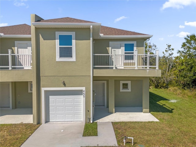 view of front of property with a front yard, a balcony, and a garage