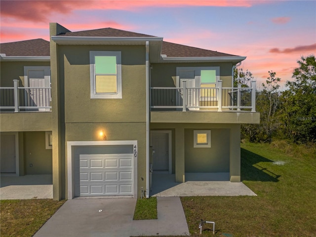 view of front of home with a balcony, a garage, and a lawn