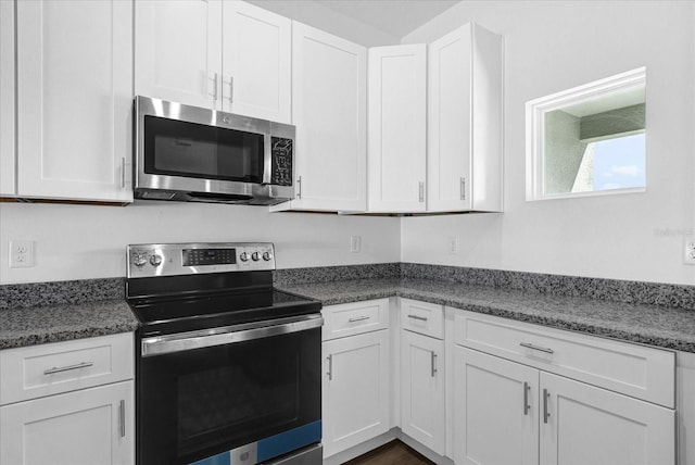 kitchen featuring white cabinets, stainless steel appliances, and dark stone countertops