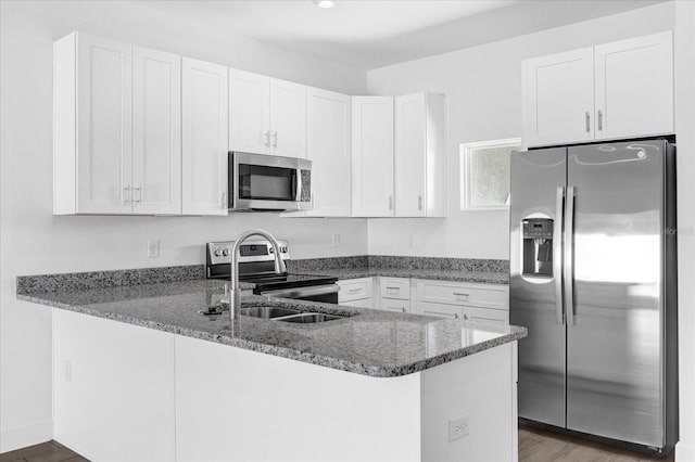 kitchen featuring stainless steel appliances, dark stone counters, and white cabinets