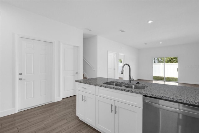 kitchen featuring sink, dishwasher, hardwood / wood-style floors, dark stone counters, and white cabinets